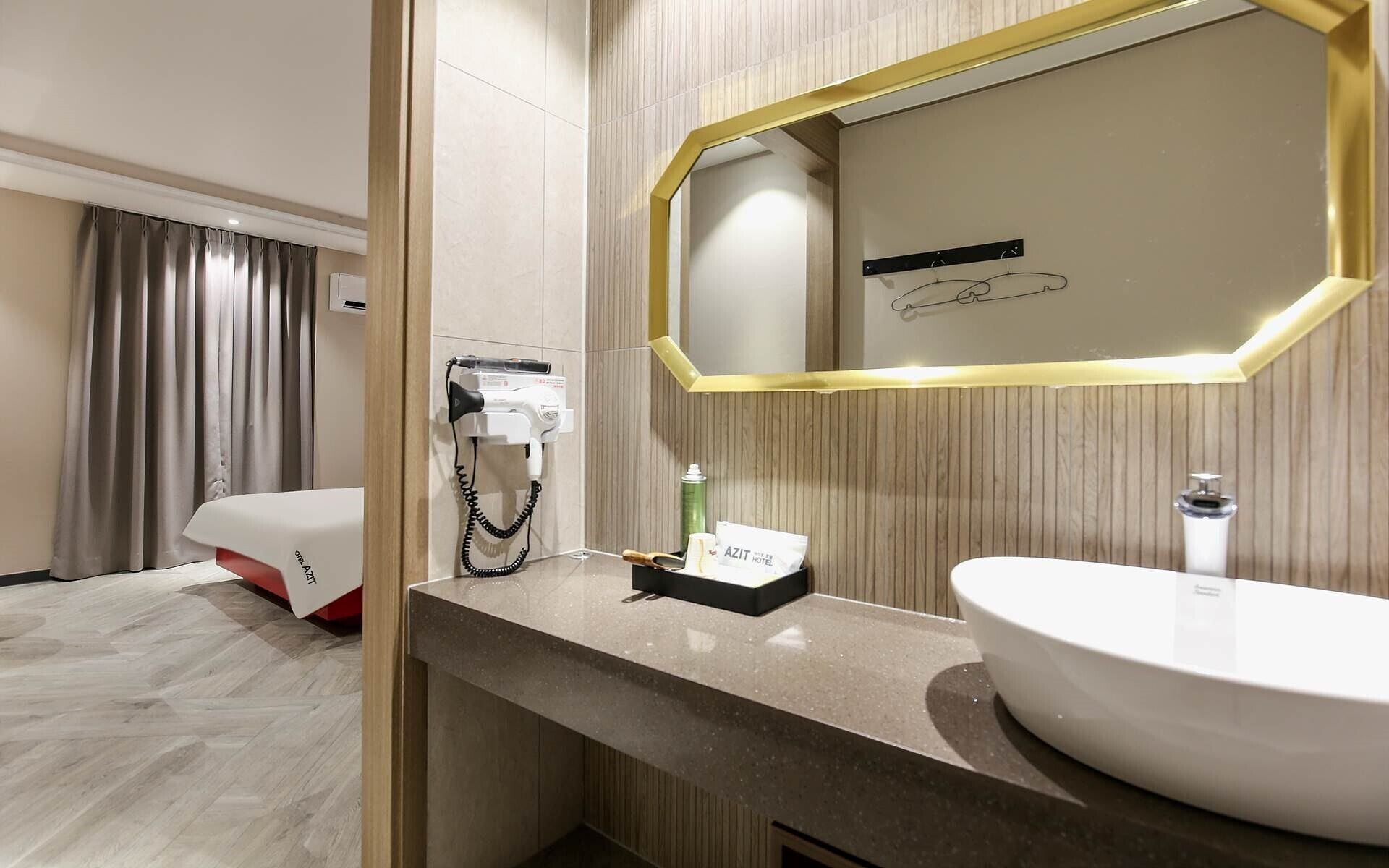 A hotel bathroom with a large mirror, a sink, and a hairdryer on the wall.