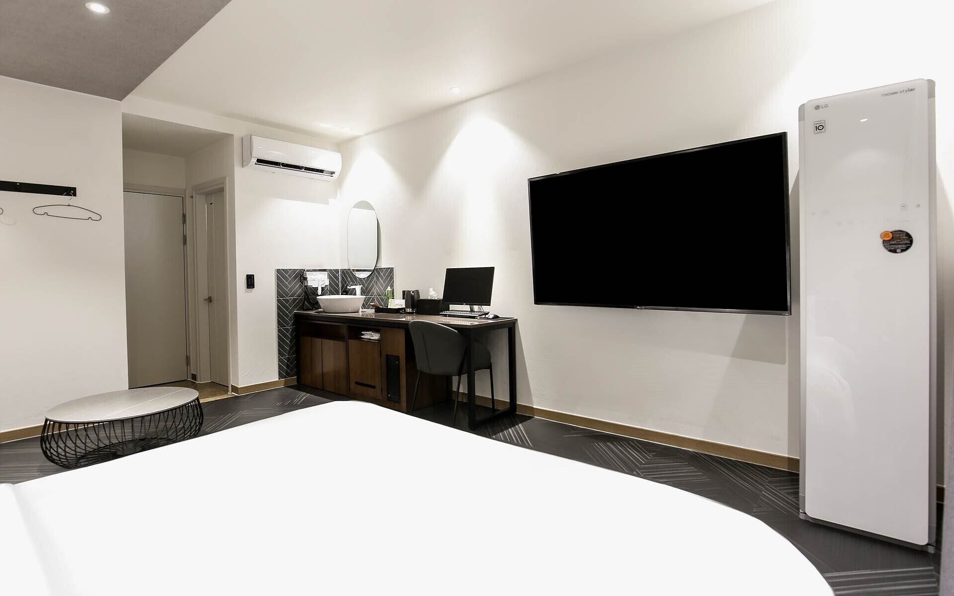 Una moderna camera d'albergo con un letto, una scrivania con un computer, una TV e un condizionatore d'aria.
