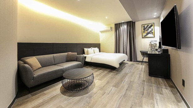 A modern hotel room with a sofa, a bed, a desk, and a TV. - Hotel Azit - Sinsigaji (Jeonju)