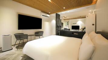 Een moderne hotelkamer met een groot bed, een flatscreen televisie, een bureau met een computer, een spiegel en een zitje.