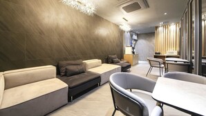 A modern lounge area with a sofa set, a dining table, and a bar area. - Hotel Azit - Sinsigaji (Jeonju)