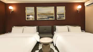 Una habitación de hotel con dos camas, una mesita redonda y tres cuadros enmarcados en la pared.
