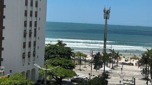 Vista costeira com um edifício alto, praia e uma estrutura em forma de coração no calçadão.