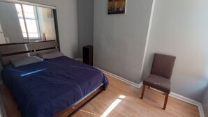 A bedroom with a bed, a chair, a small table, and a painting on the wall. - Beautiful 2 Bedroom located in a Unique Private Park. Near Beaches Near Downtown (Chicago)
