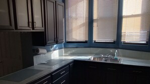 A kitchen with dark cabinets, a white countertop, and a window with blinds. - Beautiful 2 Bedroom located in a Unique Private Park. Near Beaches Near Downtown (Chicago)