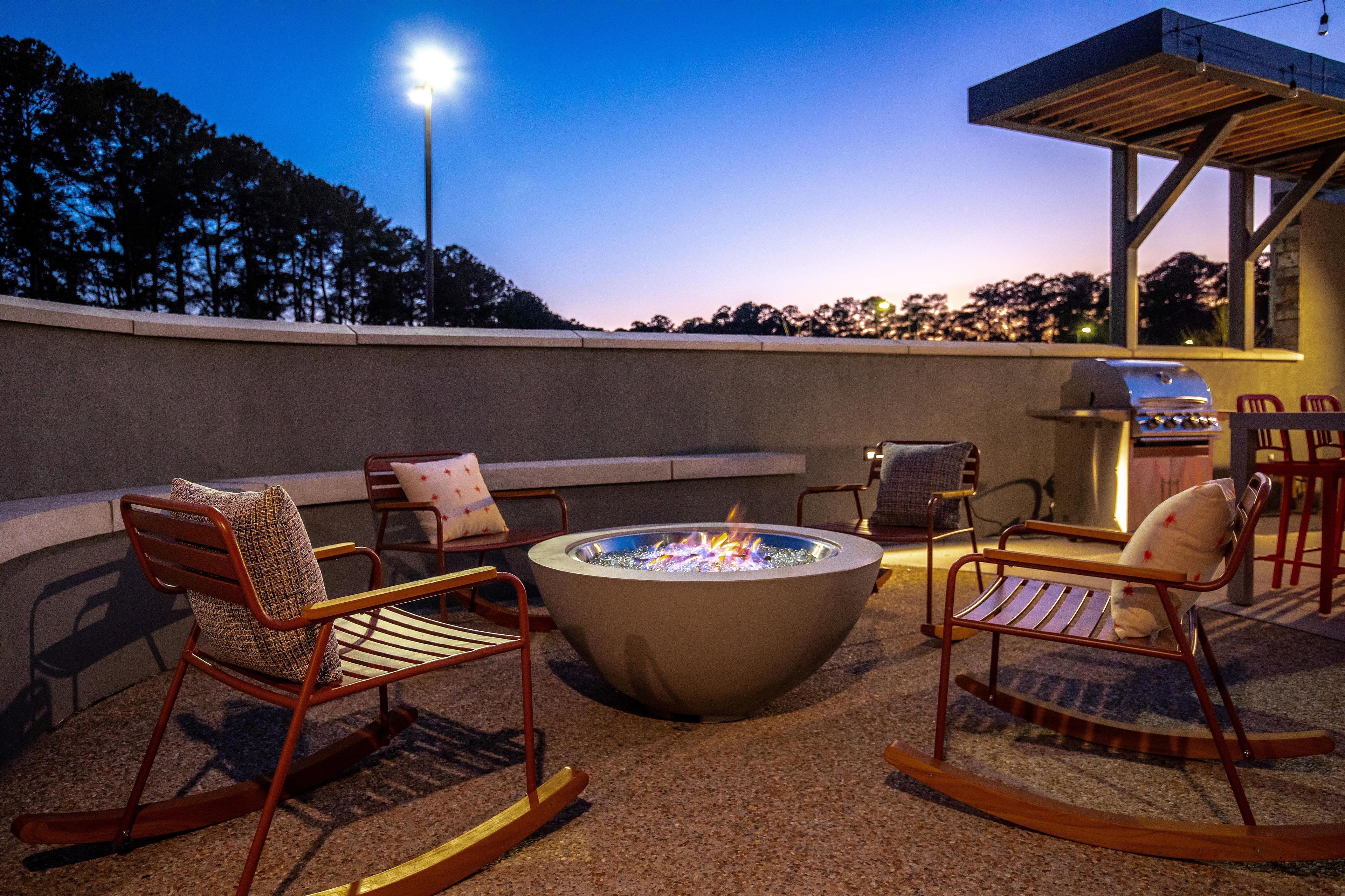An outdoor seating area with a fire pit, chairs, and a barbecue grill.