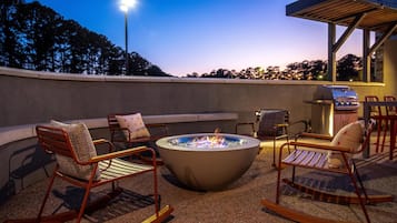 An outdoor seating area with a fire pit, chairs, and a barbecue grill.