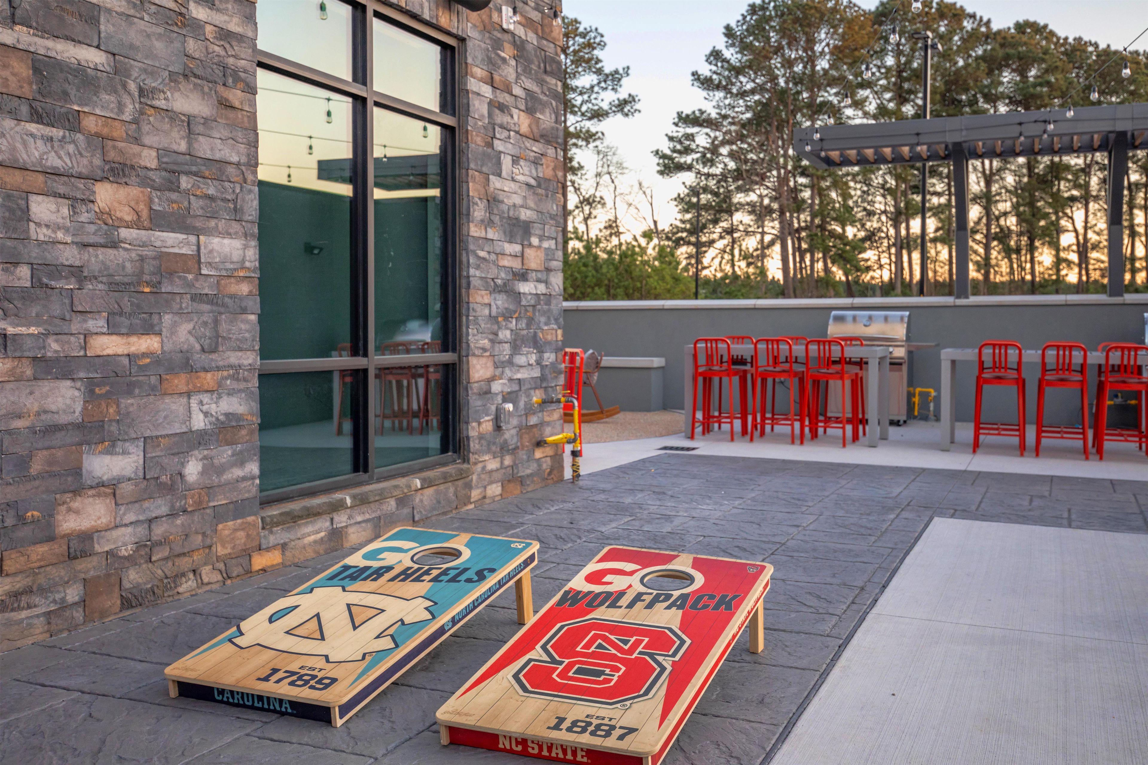 Espace extérieur aménagé avec des chaises rouges et un barbecue.