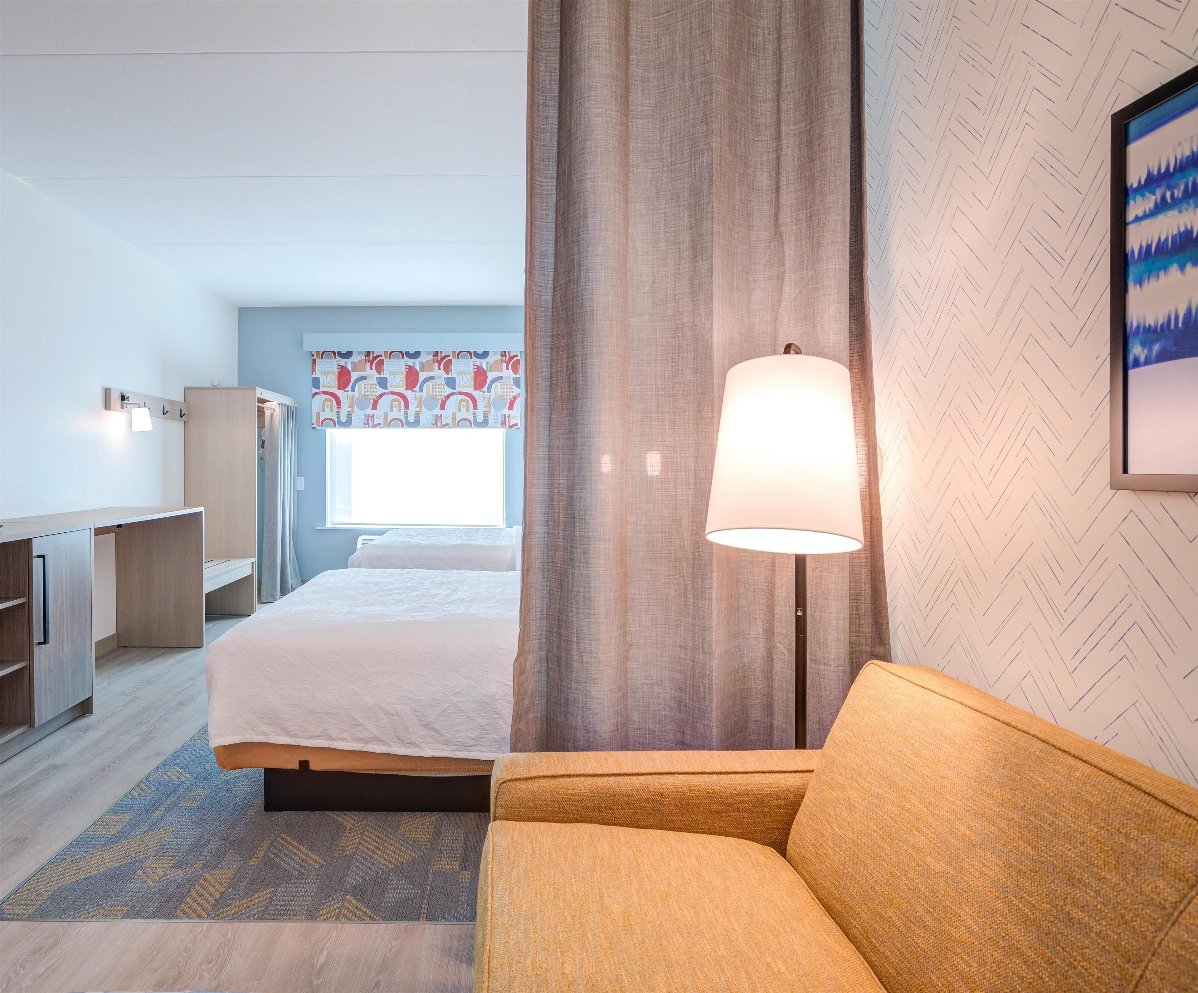 Una moderna camera d'albergo con un letto, un divano, una scrivania e una lampada.