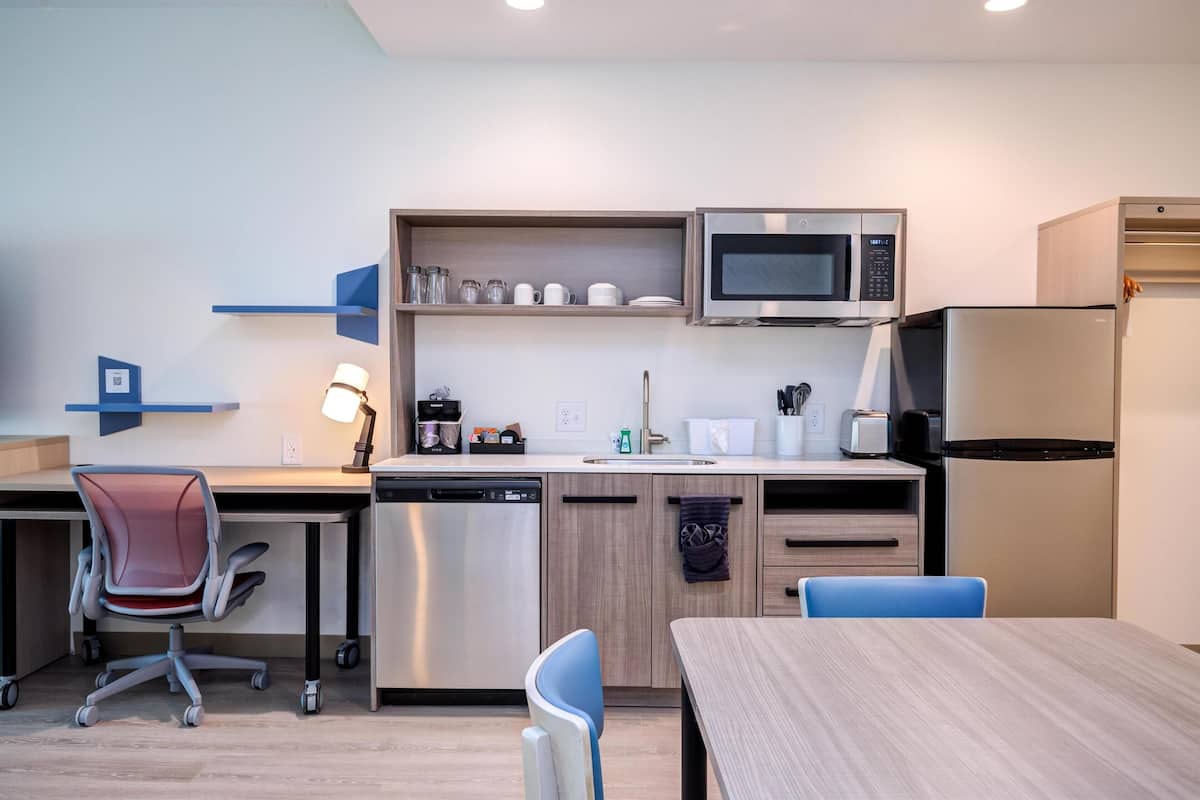A modern kitchen with a microwave, refrigerator, dishwasher, and a coffee maker.