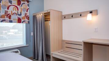 A bedroom with a bed, a wooden bench, a wardrobe, and a wall-mounted light fixture.