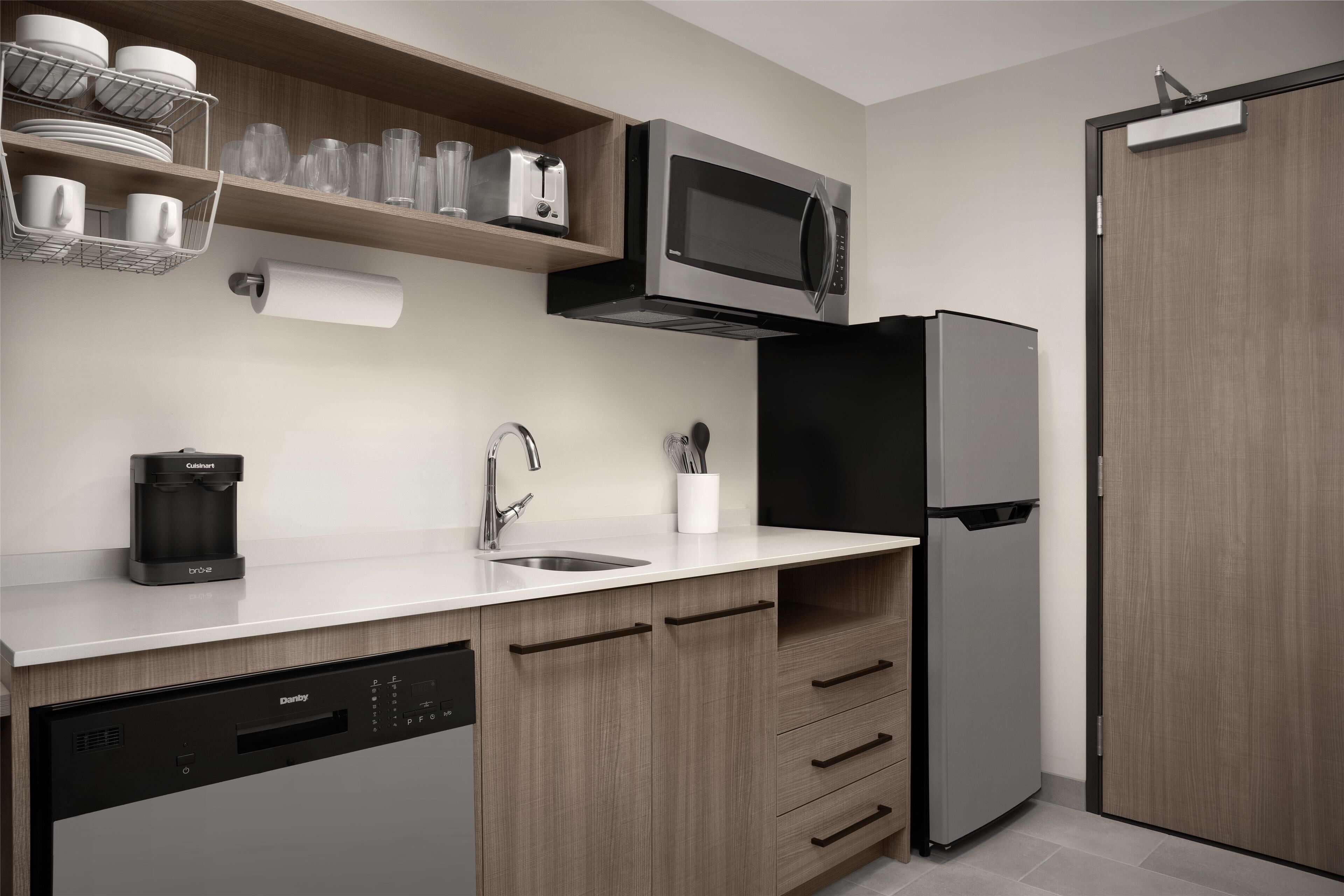 A modern kitchen with a built-in dishwasher, a coffee maker, a microwave, and a refrigerator.