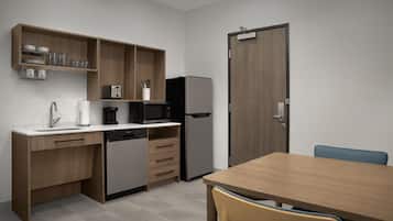 A modern kitchen with wooden cabinets, a dishwasher, a microwave, a refrigerator, and a dining table with chairs.