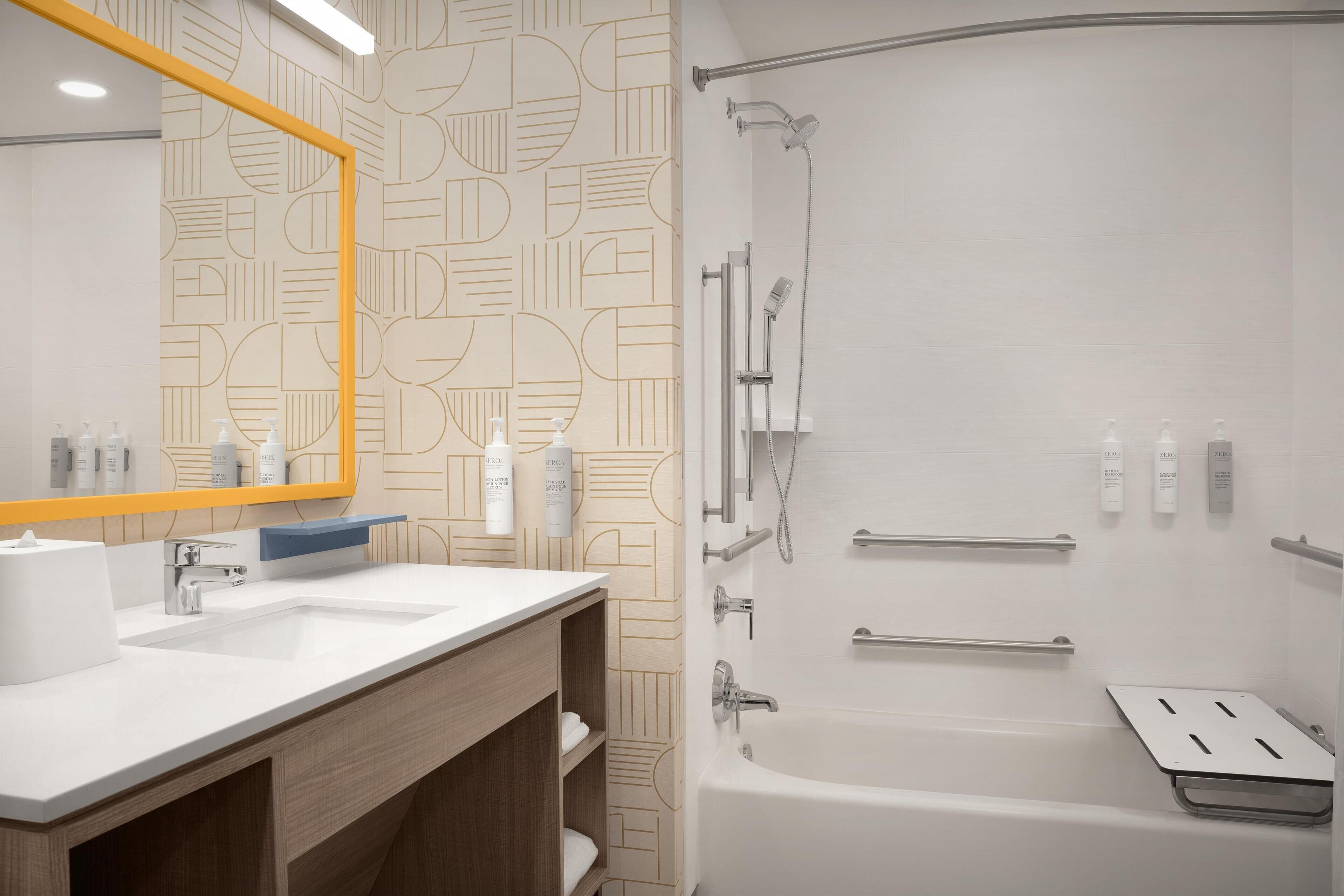 Un baño moderno con un espejo grande, dos lavamanos, una ducha con cabezal de ducha manual y una bañera.