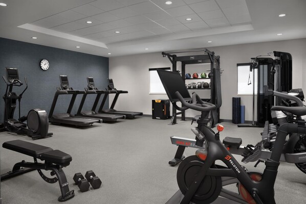 A gym with treadmills, an elliptical, a bench, dumbbells, and a Peloton bike. - Home2 Suites By Hilton Rohnert Park Sonoma County (Rohnert Park)