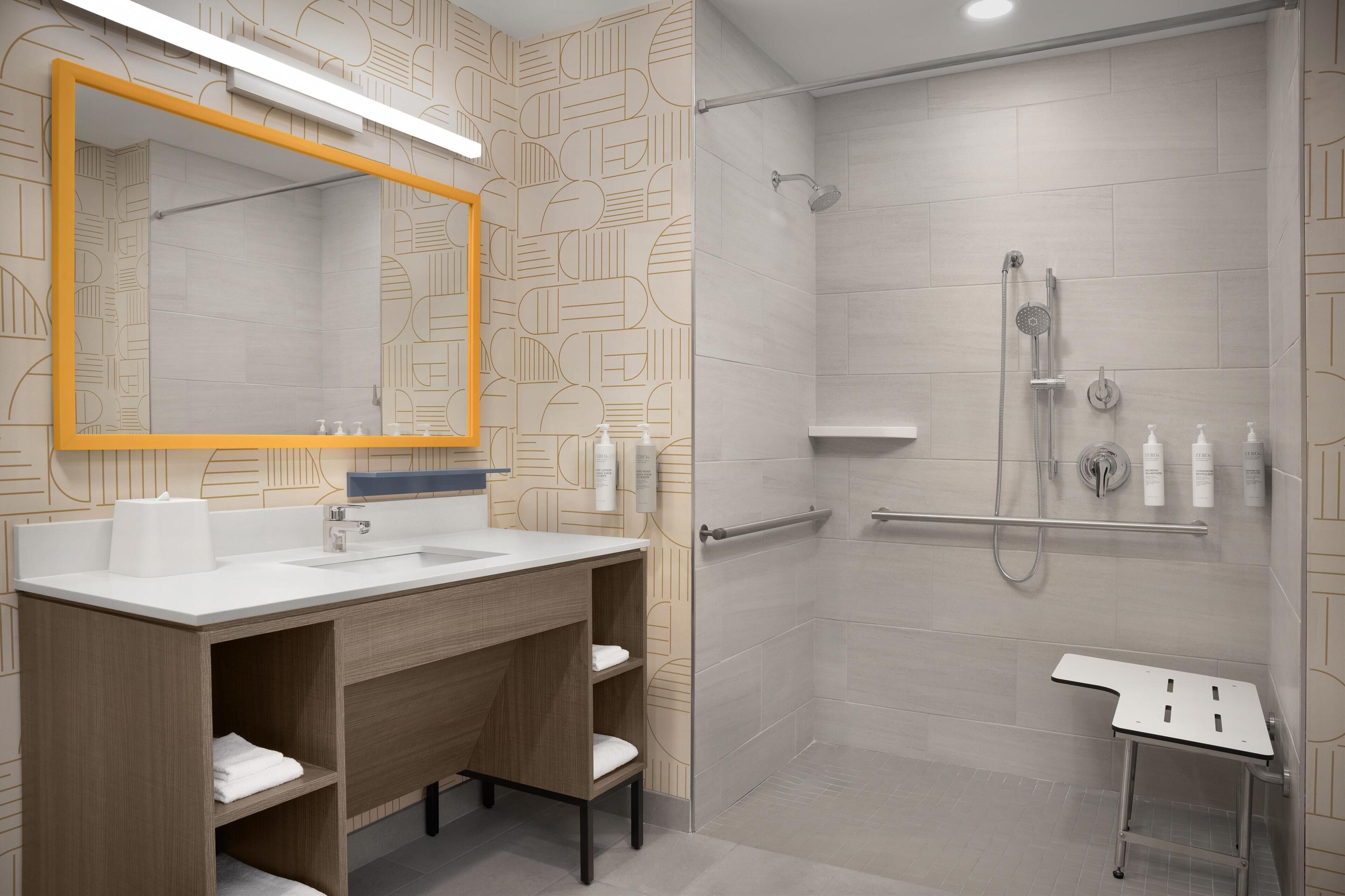 Un baño moderno con un espejo grande, un lavamanos y una zona de ducha.