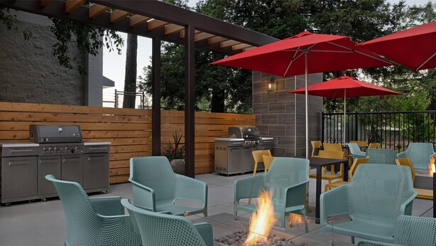 Un patio al aire libre con asientos, una parrilla y un pozo de fuego.