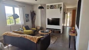 Una sala de estar moderna con un sofá, sillones, un televisor y una mesa de centro.