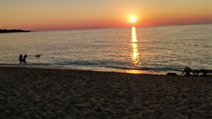 Una playa al atardecer con agua tranquila y cielo despejado.