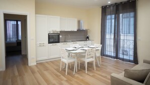 A modern kitchen with white cabinets and a dining area with a table and chairs. - Dimora Amelia Apartment 2, spacious apartment tastefully finished. (Bitonto)