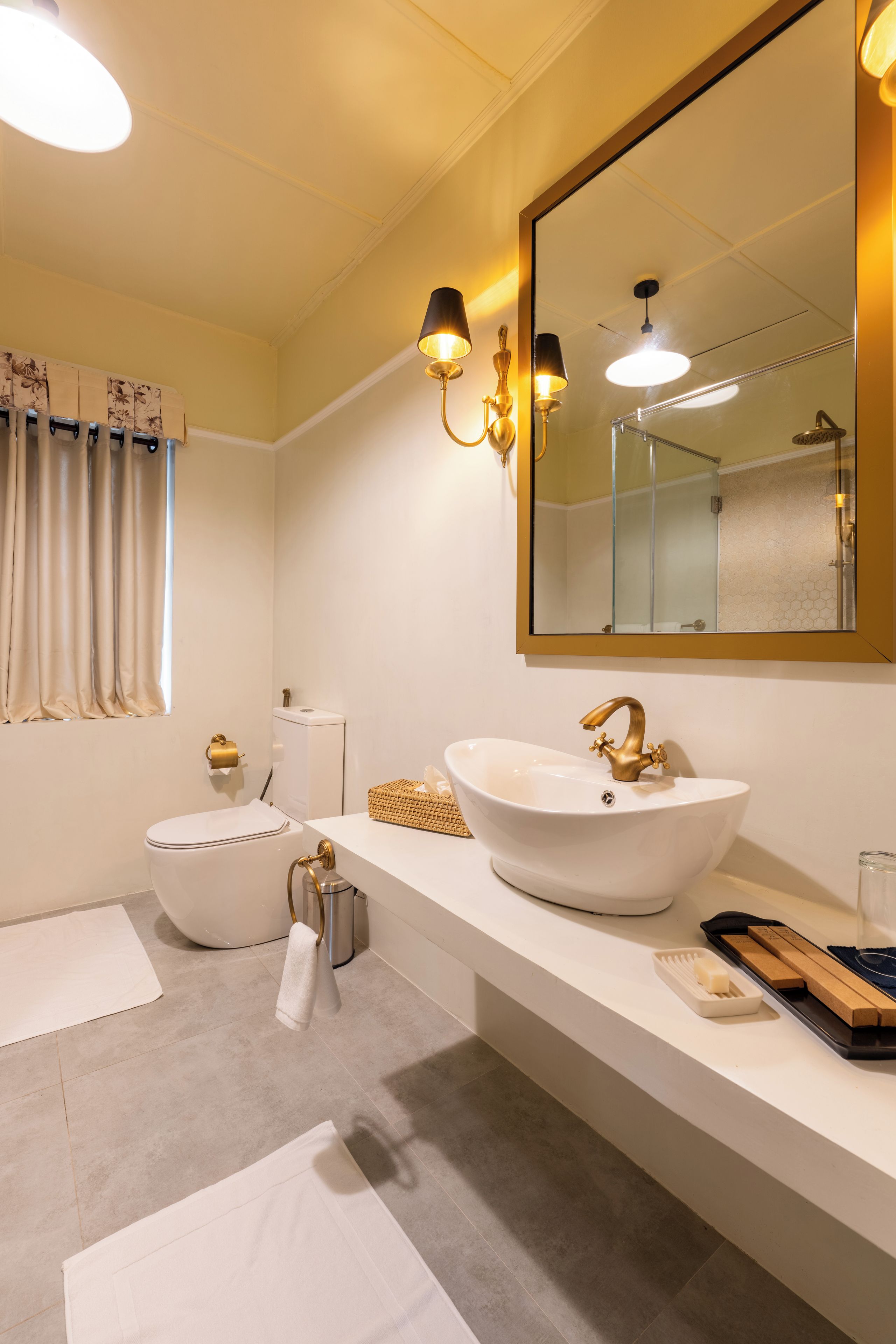 A modern bathroom with a large white sink, a toilet, a mirror, and a shower area.