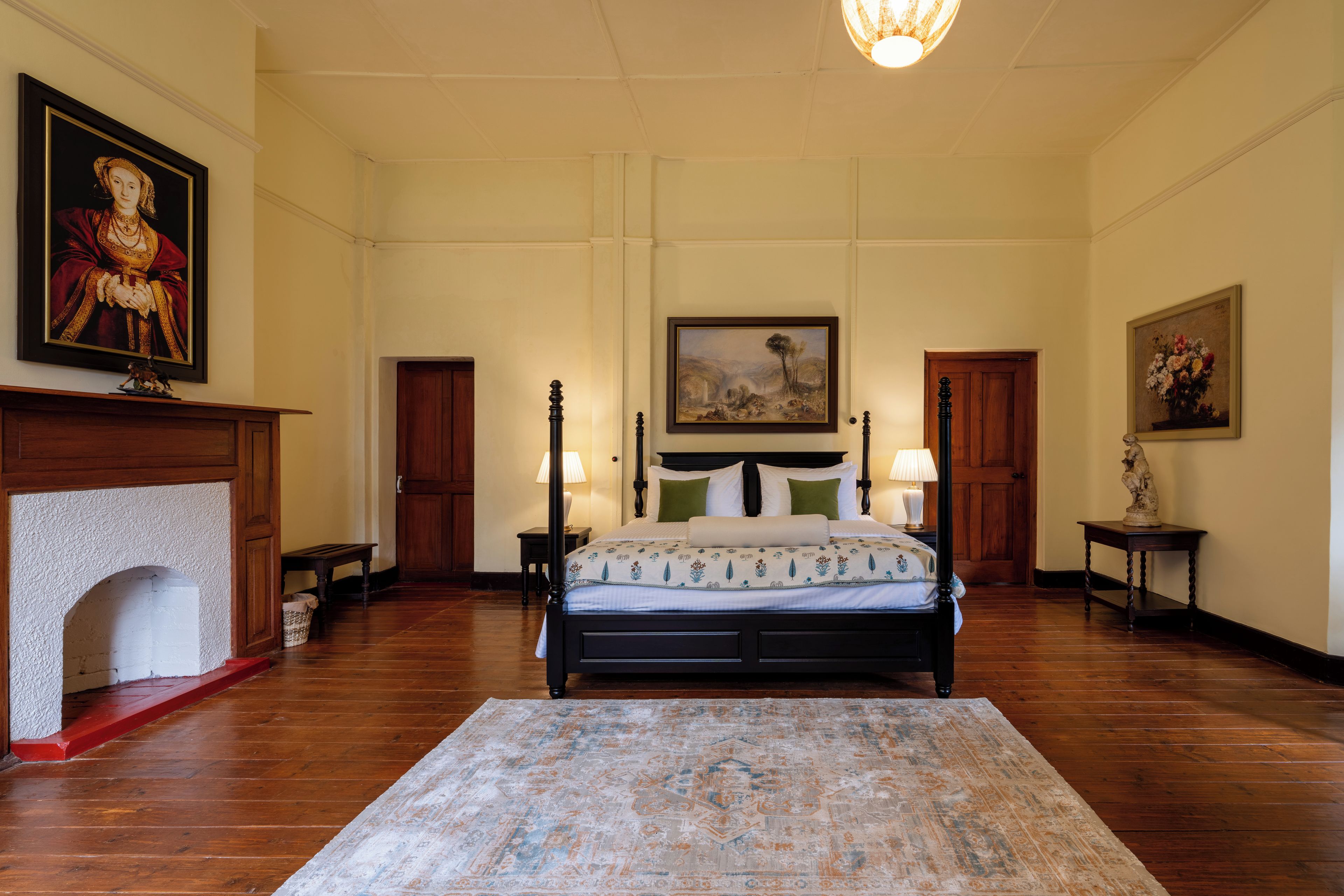 A spacious bedroom with a large bed, a fireplace, and a chandelier.