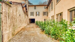Un callejón estrecho, con un edificio a la derecha y una pared a la izquierda.