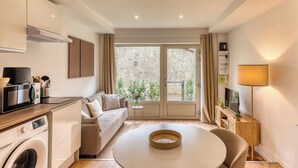 Una cocina moderna con lavadora incorporada, una zona de comedor con mesa redonda y un sofá.