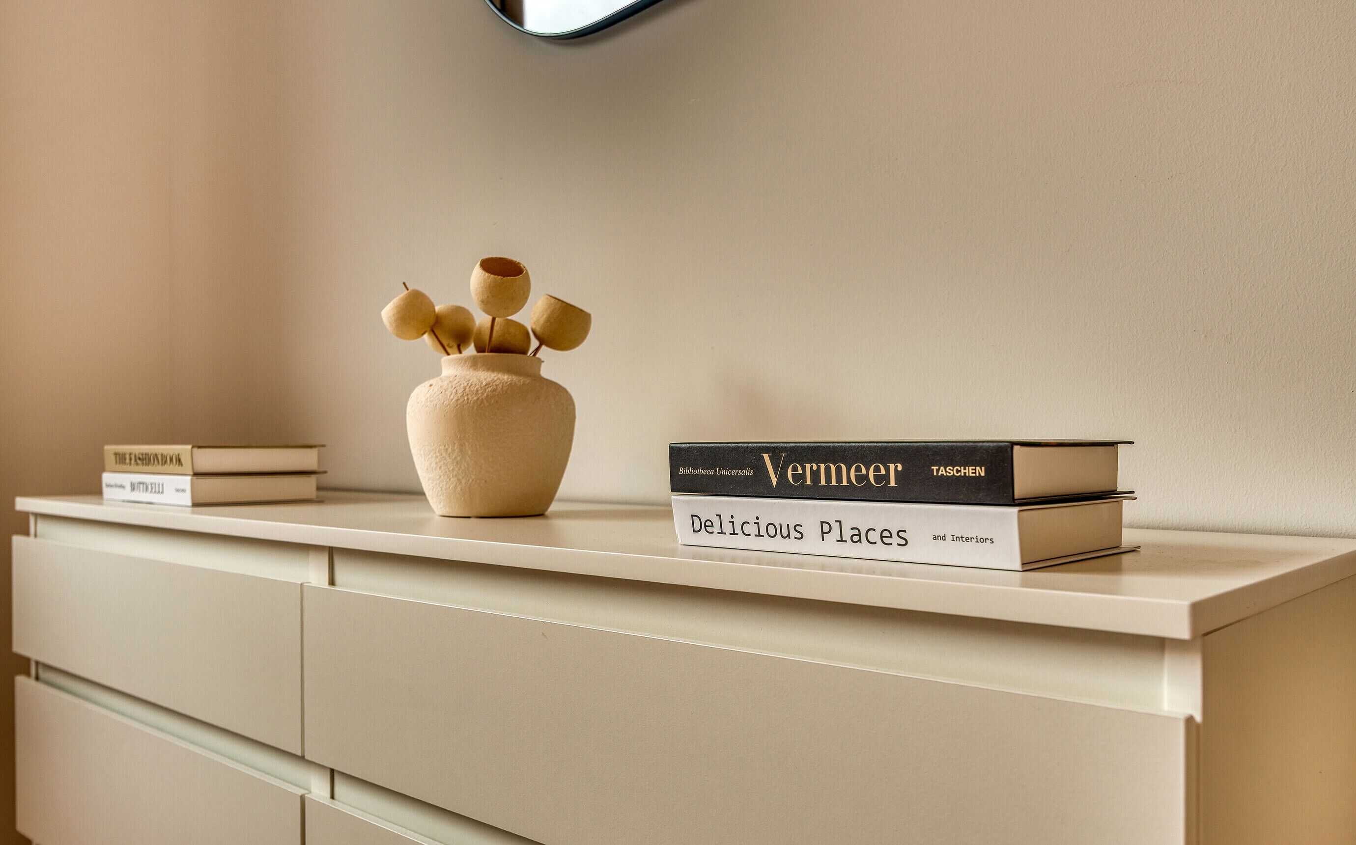 A bookshelf with books and a vase.