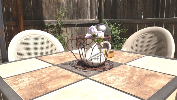 A table with a white vase and purple flowers, surrounded by two wicker chairs, set against a wooden fence. - The Tombstone Bordello  (Tombstone)
