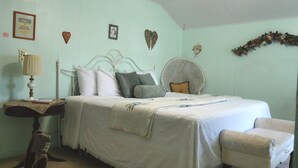 A bedroom with a bed, bedside table, lamp, and a chair. - The Tombstone Bordello  (Tombstone)