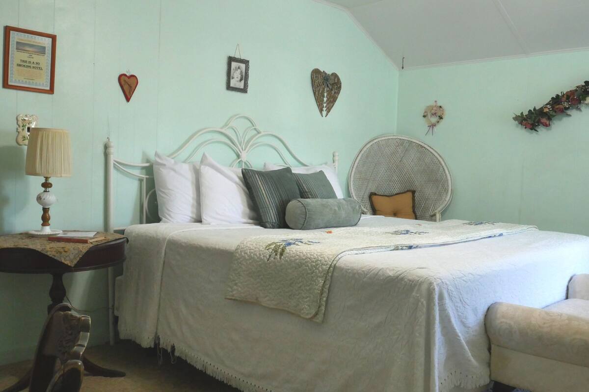 A bedroom with a bed, bedside table, lamp, and a chair.
