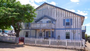 A two-story building with a balcony, a picket fence, and a tree in front. - The Tombstone Bordello  (Tombstone)