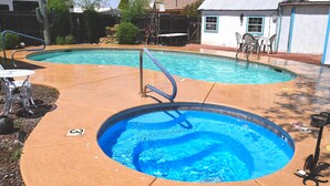 A backyard with two swimming pools, a patio table, and a small deck area. - The Tombstone Bordello  (Tombstone)