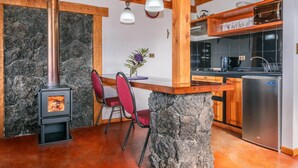 Una cocina rústica con pared de piedra, vigas de madera, estufa empotrada y electrodomésticos modernos.