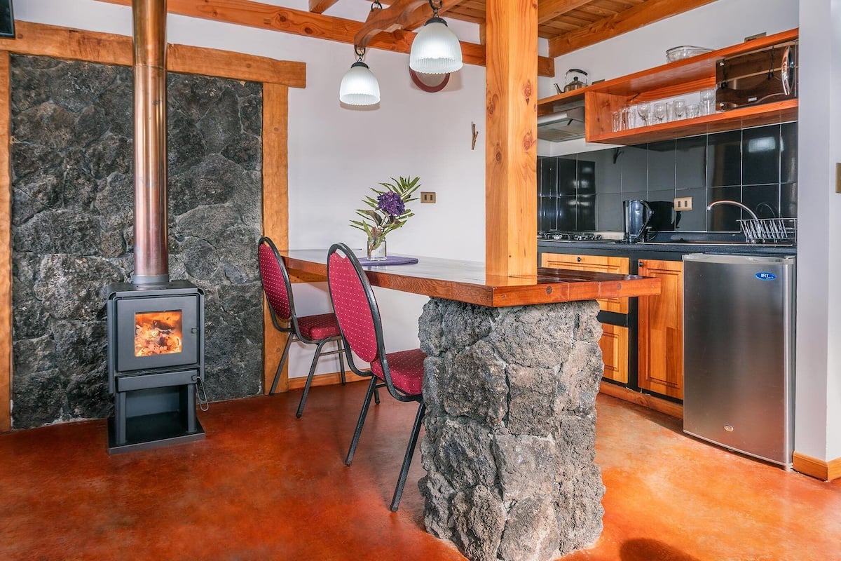 A rustic kitchen with a stone wall, wooden beams, a built-in stove, and modern appliances.