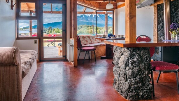 Una habitación acogedora con una mesa de piedra, un banco y vistas a las montañas.