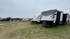 A campsite with a large RV named 'HIDEOUT' and another RV named 'BULLET'. - RV Spot #5 @ The Halles (Round Top)