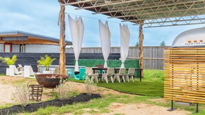 Terrassa exterior amb zona d'estar coberta, una barbacoa i una font.
