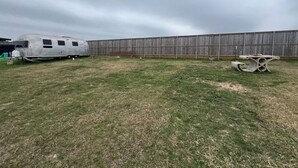 Un jardí amb gespa, una caravana blanca i una tanca de fusta.