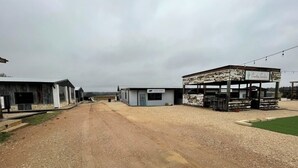 Camí rural flanquejat per edificis, entre ells una botiga petita amb un rètol.