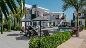 A modern hotel with a pool, lounge chairs, and umbrellas. - Genesis Residences 
Meads Bay 1 - Downstairs Unit  (The Cove)