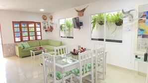 A living room with a green sofa, white chairs, a glass-top coffee table, and a TV mounted on the wall. - Private house with pool - Riohacha, La Guajira. Colombia (Riohacha)