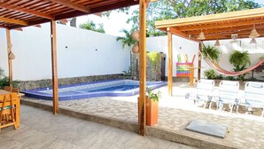 A covered outdoor area with a swimming pool, wooden pergola, lounge chairs, and potted plants. - Private house with pool - Riohacha, La Guajira. Colombia (Riohacha)