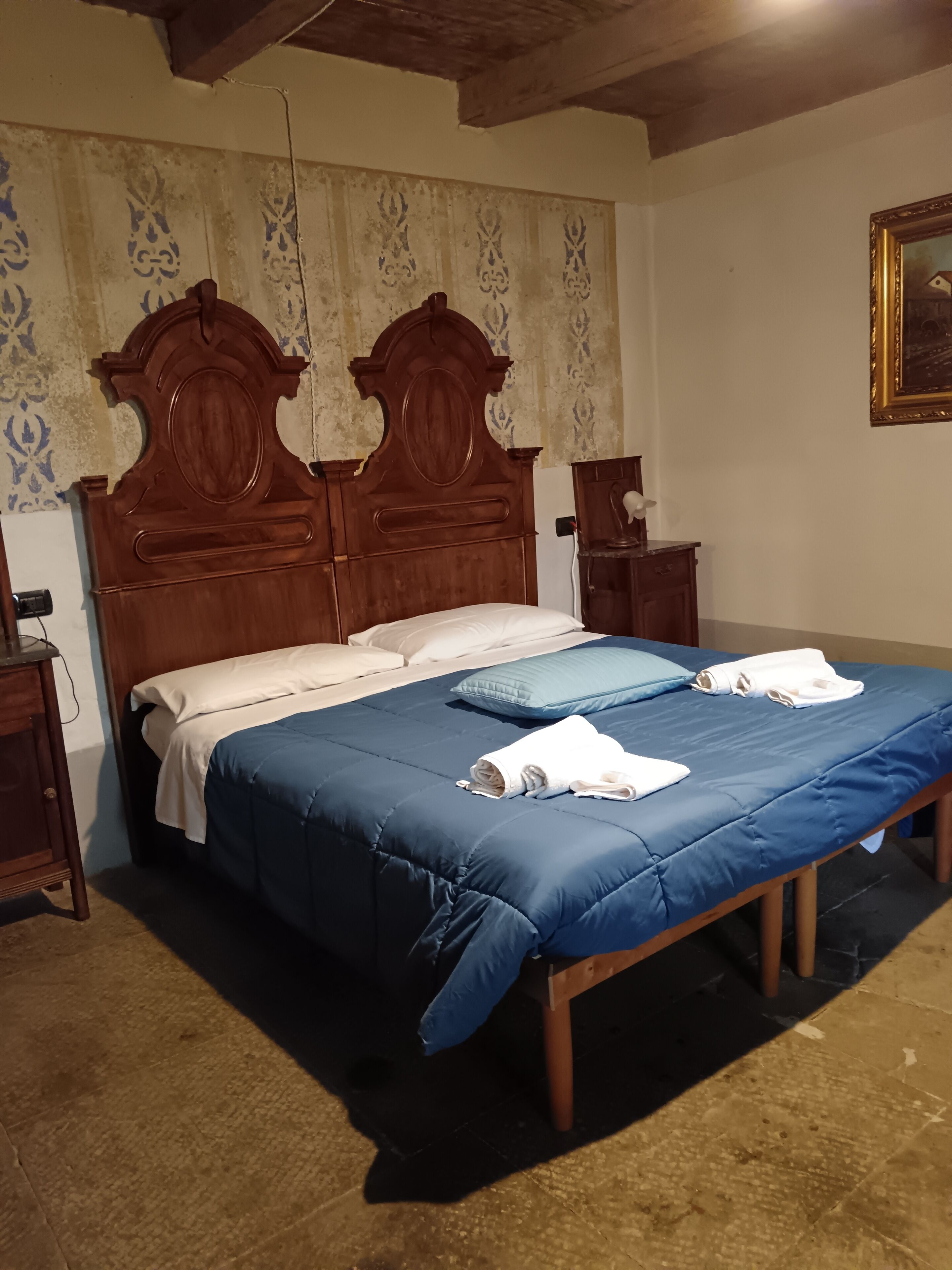 Una camera da letto con un letto in legno, due comodini, un tavolino e un quadro appeso al muro.