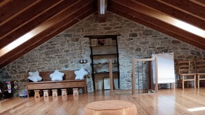 Une pièce mansardée spacieuse, avec un plancher en bois, un mur en pierre et une cheminée.