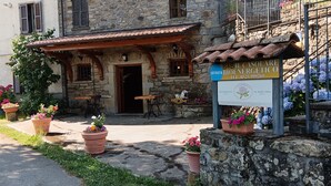 Un bâtiment rustique avec une façade en pierre, une porte d’entrée en bois et une enseigne indiquant qu’il s’agit d’un établissement proposant des chambres et le petit-déjeuner.