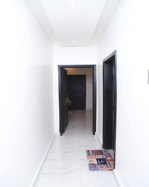 Leading to a space, this hallway features a tiled floor and a door at the end.