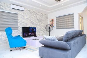 Relax in this stylish living room with a flat-screen TV, comfortable sofa, and a cozy armchair.