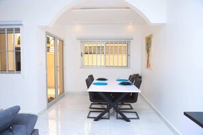 Enjoy meals in this stylish dining area with a table for four, black chairs, and a beautiful painting on the wall.